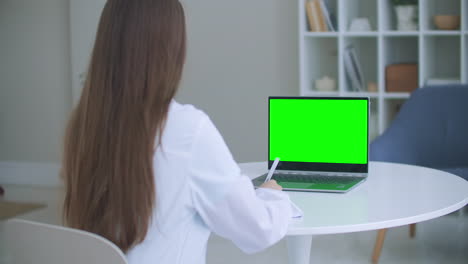 Ärztin-Berät-Online-Laptop-Mit-Grünem-Bildschirm-Auf-Dem-Tisch-Chroma-Key-Konzept